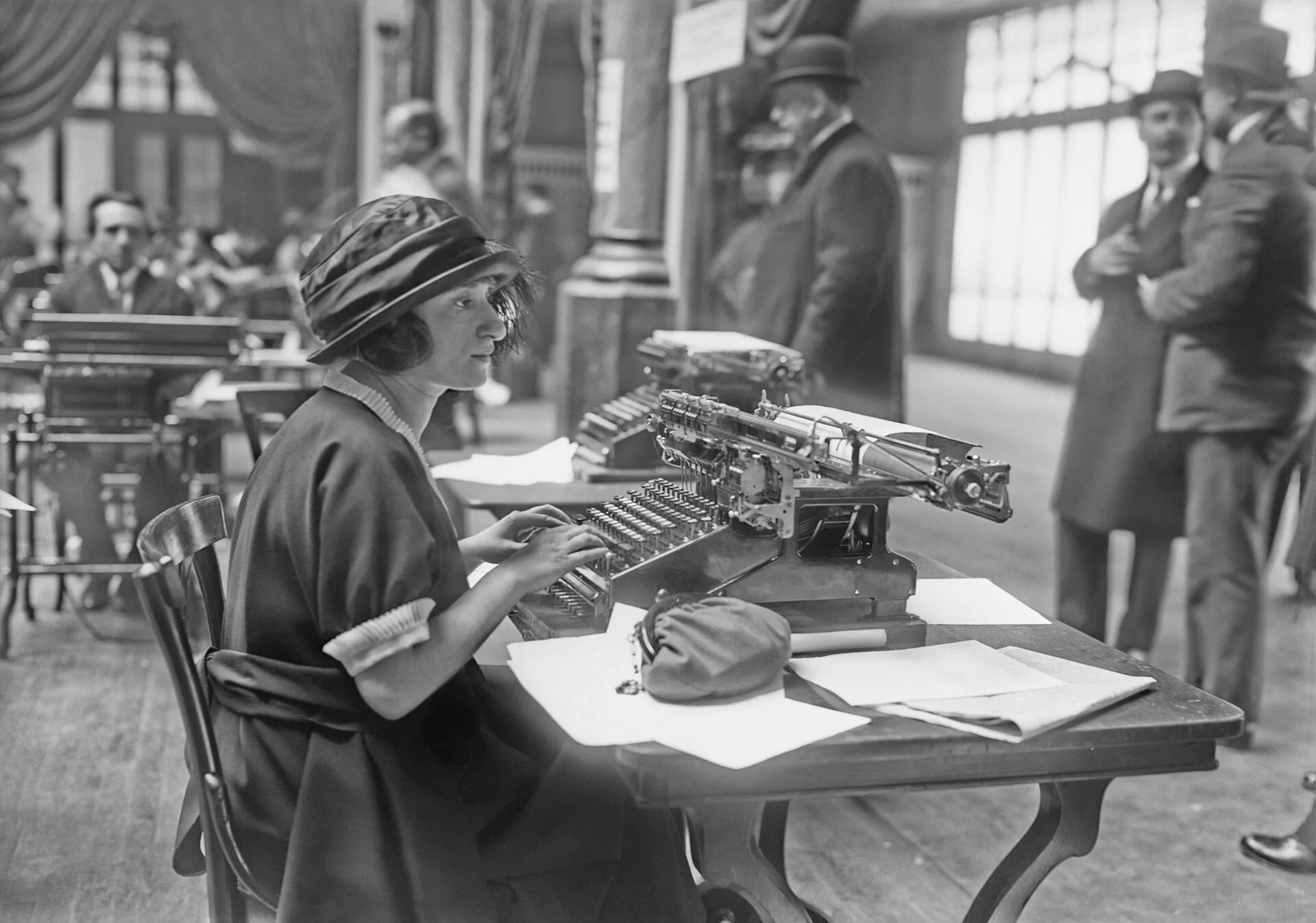 Una mujer escribe a máquina en un concurso, con público detrás